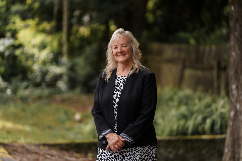 Paralegal, Tammy Brown, standing outside, smiling, with greenery behind her