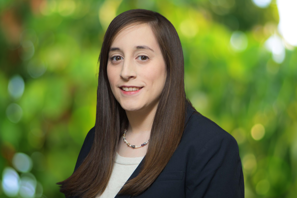 Sarah Carter, Associate Attorney at Novey Law, in black blazer with blurred green background