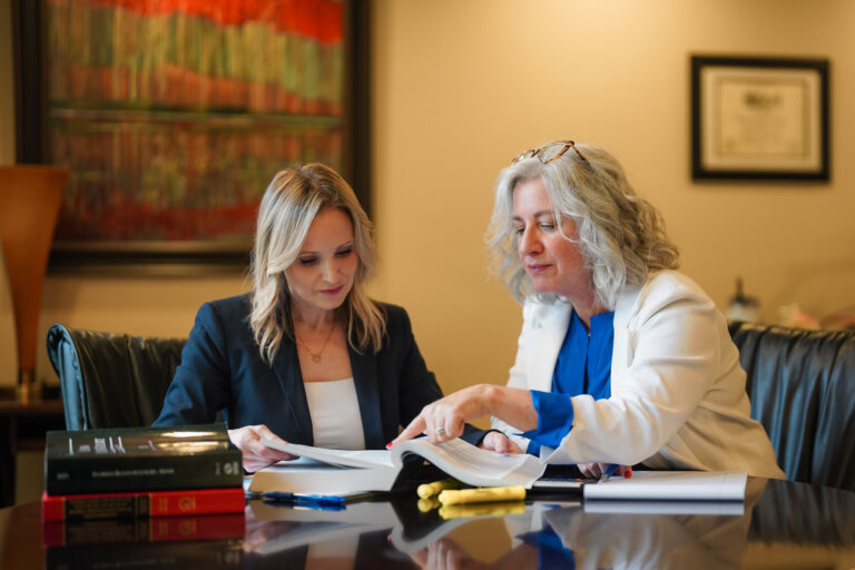 Photo of Christin Gonzalez and Shannon Novey reading a book together for their Family Law firm Novey+Gonzalez.